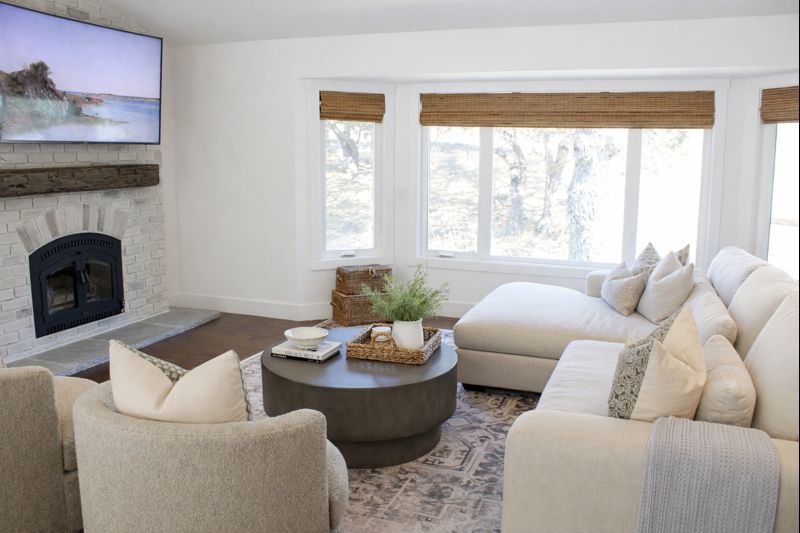 Neutral living room with custom furniture, textured area rug, round coffee table, and white brick fireplace styled by Cadwell & Co.